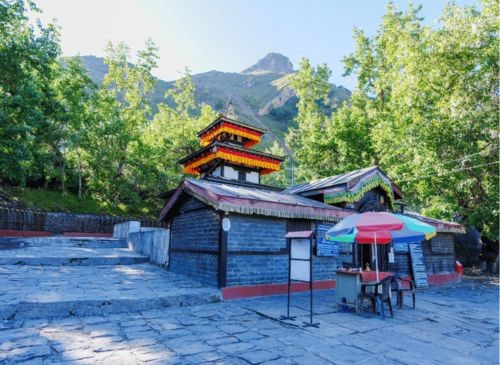 A breathtaking view of Muktinath Temple in Mustang, Nepal, showcasing its unique architecture and the surrounding mountainous landscape. Pilgrims and visitors can be seen near the temple, adding to the serene and spiritual atmosphere of the region.